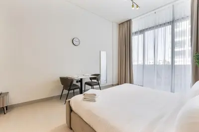 a bedroom with a bed and a table and a window at ALiving Cozy Studio I Binghatti Galaxy, JVC- G02 in Dubai