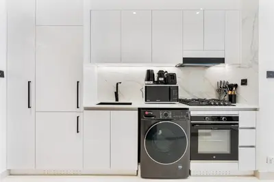 a white kitchen with a stove and a dishwasher at ALiving Cozy Studio I Binghatti Galaxy, JVC- G02 in Dubai
