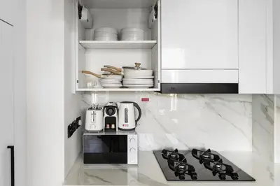 a white kitchen with a stove and a microwave at New! Cozy 1BR in Binghatti House Pool and Gym in JVC in Dubai