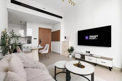 a living room with a couch and a tv on a wall at New! Cozy 1BR in Binghatti House Pool and Gym in JVC in Dubai