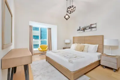 a bedroom with a large bed and a yellow chair at Vacay Lettings - Elite Residence - 1 BR - Partial Sea View in Dubai
