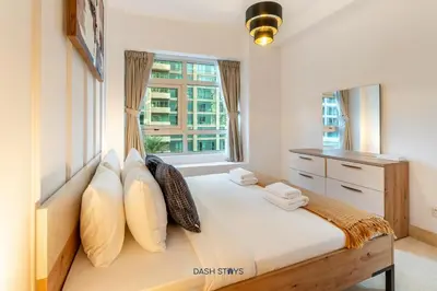 a bedroom with a bed with pillows and a window at Lux 2BR in Dubai Marina Walk to Beach & Metro in Dubai