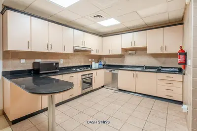 a kitchen with white cabinets and a black counter top at Lux 2BR in Dubai Marina Walk to Beach & Metro in Dubai