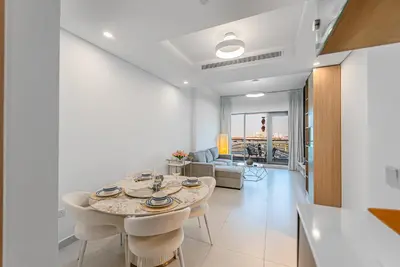a white living room with a table and chairs at Escape24 Elegant 1BR with City View near Dubai Mall in Dubai