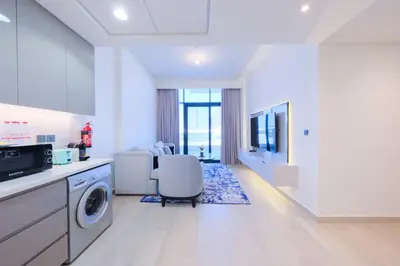 a kitchen with a washing machine and a chair in it at Spacious 2BHK at Azizi Riviera 22 Meydan in Dubai