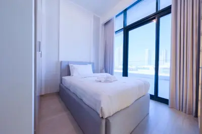 a bedroom with a white bed with a large window at Spacious 2BHK at Azizi Riviera 22 Meydan in Dubai