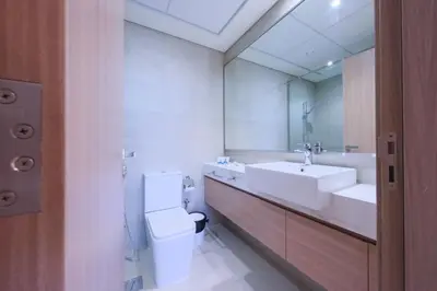 a bathroom with a toilet and a sink and a mirror at Spacious 2BHK at Azizi Riviera 22 Meydan in Dubai