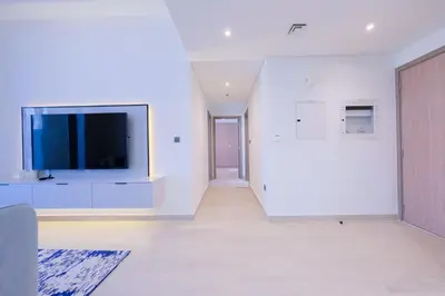 a living room with a flat screen tv on a white wall at Spacious 2BHK at Azizi Riviera 22 Meydan in Dubai