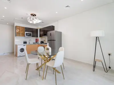 a dining room with a glass table and white chairs at Blissful Retreat 1BR with 1GR Study Sleeps 4 in Gemz 05 in Dubai
