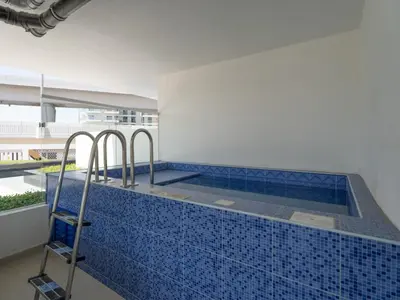 a swimming pool with a blue tile floor and a ladder at Blissful Retreat 1BR with 1GR Study Sleeps 4 in Gemz 05 in Dubai