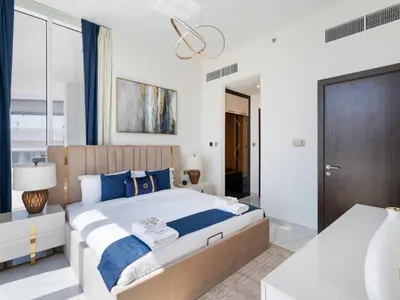 a bedroom with a large bed with blue pillows at Blissful Retreat 1BR with 1GR Study Sleeps 4 in Gemz 05 in Dubai