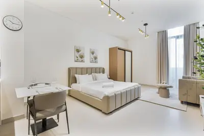 a white bedroom with a bed and a desk at ALiving Brand New & Modern Studio I Binghatti Galaxy, JVC- G01 in Dubai