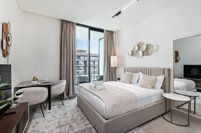 a hotel room with a bed and a desk and a window at Stylish 1BR Studio Unit Balcony & Pool in Dubai