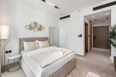 a white bedroom with a large bed in a room at Stylish 1BR Studio Unit Balcony & Pool in Dubai