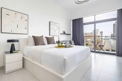 a white bedroom with a large bed and a large window at Frank Porter - Oxford Boulevard in Dubai