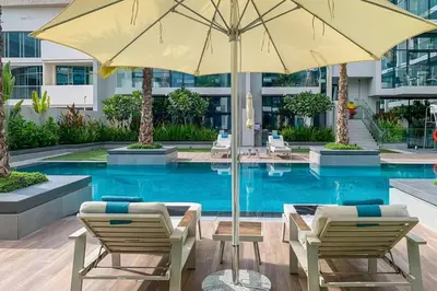 a swimming pool with two chairs and an umbrella at Frank Porter - Oxford Boulevard in Dubai