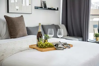 a tray of grapes and wine glasses on a bed at Frank Porter - Oxford Boulevard in Dubai