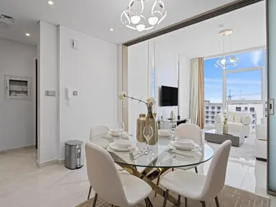 a dining room with a glass table and white chairs at Velvet Luxe Modern - 1BR w Private Pool in Gemz-15 in Dubai