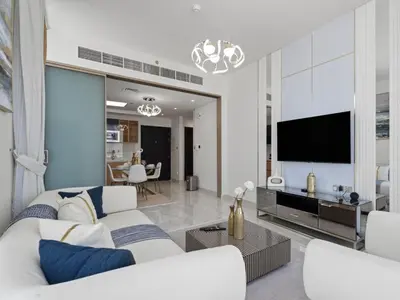 a living room with a white couch and a tv at Velvet Luxe Modern - 1BR w Private Pool in Gemz-15 in Dubai