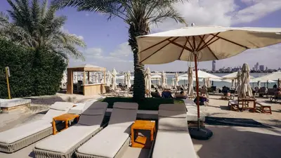 a group of white lounge chairs and an umbrella at Luxury Palm Jumeirah Apartment with Sea Views Balqis Residence in Dubai
