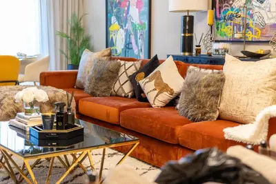 a living room with an orange couch with pillows at Luxury Palm Jumeirah Apartment with Sea Views Balqis Residence in Dubai