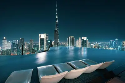 a rooftop with chairs and a city skyline at night at Famous Sky Pool - Paramount Midtown - Dubai Skyline Views in Dubai