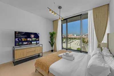 a bedroom with a large bed and a flat screen tv at Charming Studio in Binghatti Galaxy JVC in Dubai