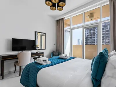 a bedroom with a bed with a desk and a tv at Glamorous Luxe Studio in Ghalia-JVC-12 in Dubai