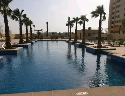 a large swimming pool with palm trees in a resort at Glamorous Luxe Studio in Ghalia-JVC-12 in Dubai