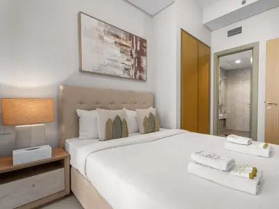 a bedroom with a large white bed and a night stand at Sophisticated 2BDR Living In Aykon City Business B in Dubai