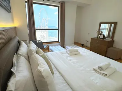 a large white bed in a room with a large window at JBR l Full Sea View l 4BR l 3min to Beach l 7-12PAX in Dubai