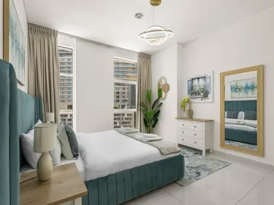 a bedroom with a bed and a desk and windows at Signature Prestige 1BR Sleeps 4 -Damac Central in Dubai