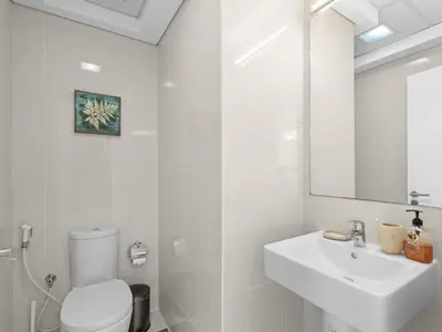 a white bathroom with a toilet and a sink at Signature Prestige 1BR Sleeps 4 -Damac Central in Dubai