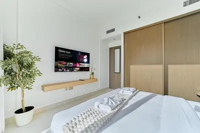 a bedroom with a bed with a tv on the wall at Luxury 3BR Marina View at Palace Beach Residence in Dubai