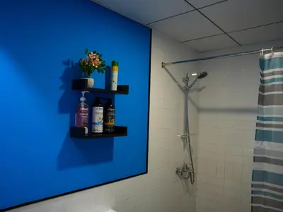 a bathroom with a blue wall with a shelf with bottles at 2BR Next to Metro and EXPO City GYM Pool Playground in Dubai