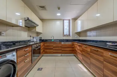 a large kitchen with wooden cabinets and a dishwasher at New! Serene 2BR with Balcony & Pool in Sparkle Tower in Dubai