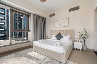 a bedroom with a bed and a large window at New! Serene 2BR with Balcony & Pool in Sparkle Tower in Dubai
