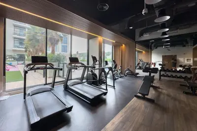 a gym with treadmills and ellipticals in a room at New! Stylish 1BR with Balcony and Pool Elysee III JVC in Dubai