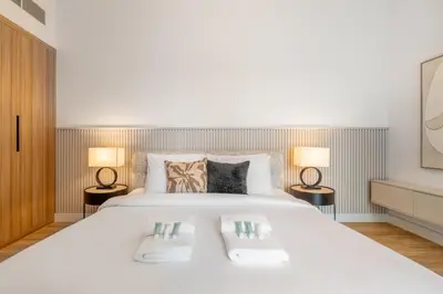 a bedroom with a large white bed with two lamps at New! Stylish 1BR with Balcony and Pool Elysee III JVC in Dubai