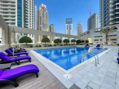 a large swimming pool with purple lounge chairs and buildings at Royal oceanic Dubai marina in Dubai