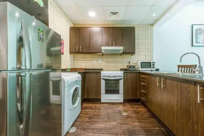 a kitchen with a stainless steel refrigerator and wooden cabinets at Royal oceanic Dubai marina in Dubai