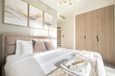 a bedroom with a white bed with a wooden cabinet at Brand New Luxury Waterfront 2bd Beautiful Canal View in Dubai