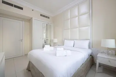 a white bedroom with a large white bed with white pillows at Damac Maison Mall Street! Upgraded 3 Bedroom with Burj and DIFC views! Nearest to Dubai Mall in Dubai