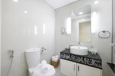 a white bathroom with a toilet and a sink at Damac Maison Mall Street! Upgraded 3 Bedroom with Burj and DIFC views! Nearest to Dubai Mall in Dubai
