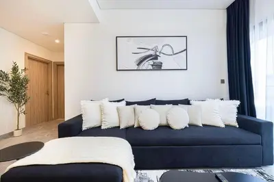 a living room with a blue couch with white pillows at Luxury 3 Bedroom Apartment, 8 mins from Dubai Mall, Sleeps 6 people in Dubai