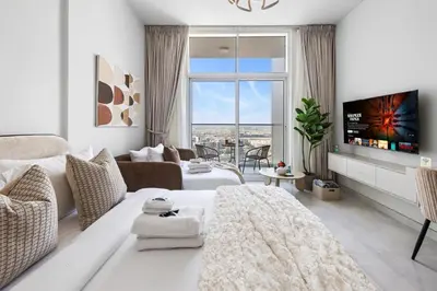 a white living room with a tv and a couch at Cozy Studio with 31st Floor Miracle Garden View in Dubai