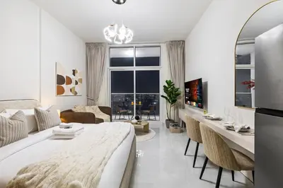 a white living room with a large bed and chairs at Cozy Studio with 31st Floor Miracle Garden View in Dubai