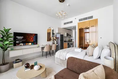 a bedroom with a large bed and a living room at Cozy Studio with 31st Floor Miracle Garden View in Dubai