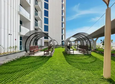 two benches on the side of a building with grass at Cozy Studio with 31st Floor Miracle Garden View in Dubai