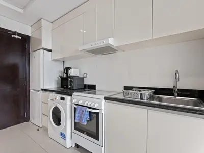 a white kitchen with a washing machine and a sink at Relaxing Stay Studio in Ghalia 29 in Dubai